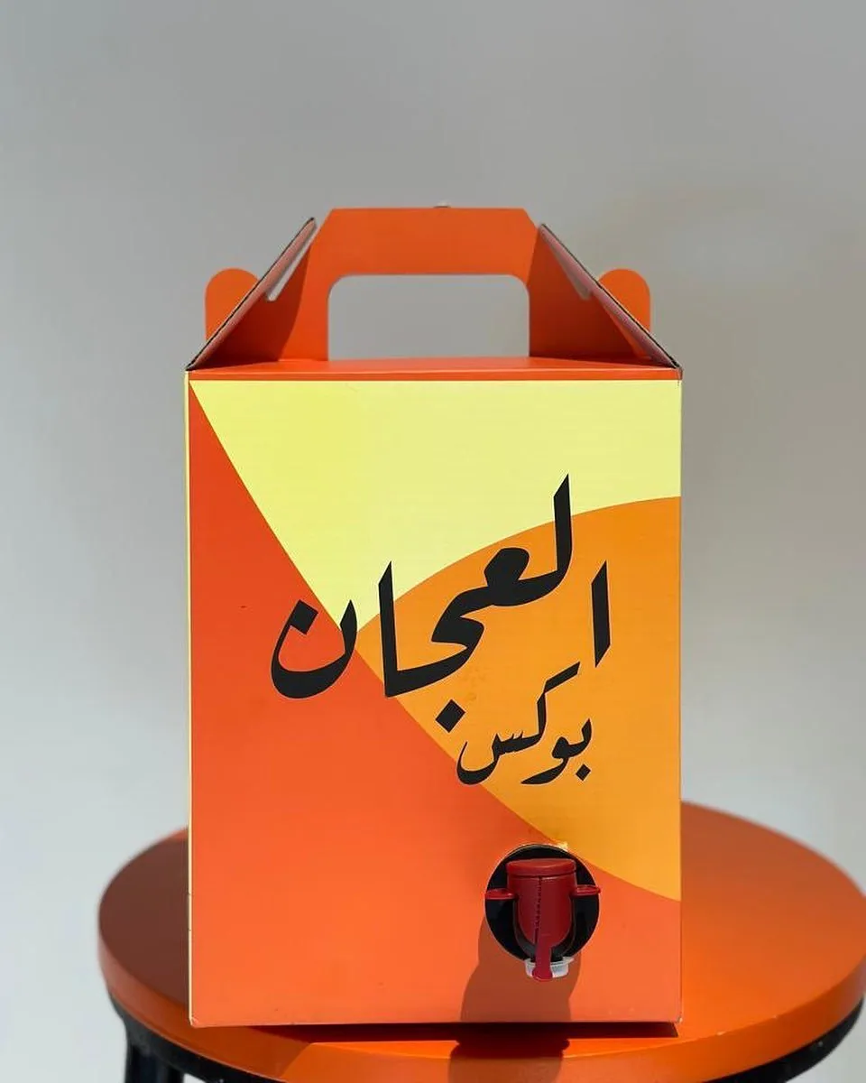 بوكس كرتون برتقالي بمقبض علوي وحنفية صب حمراء، مطبوع بألوان كاملة باسم تجاري عربي