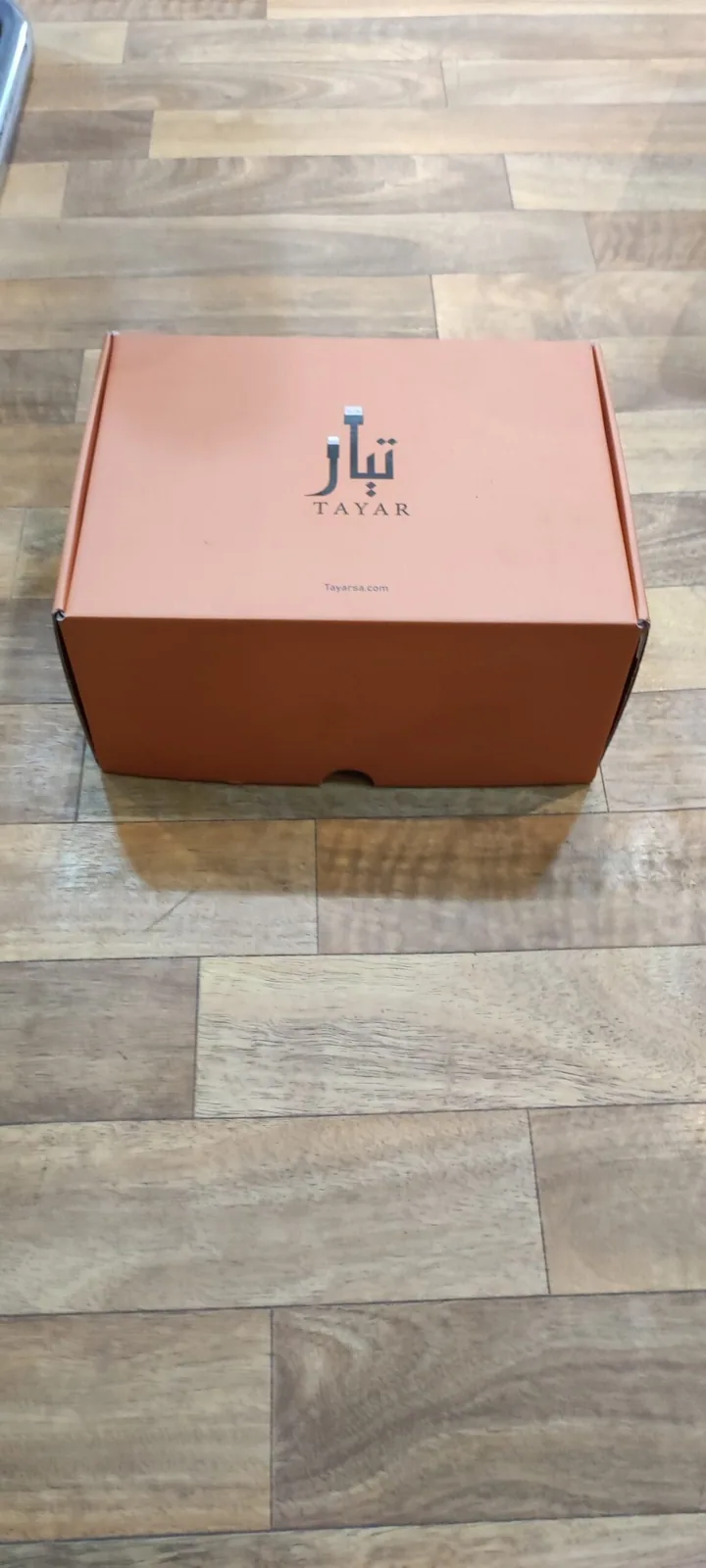 بوكس شحن كرتوني مطبوع باللون البرتقالي بشعار متجر إلكتروني، مغلق ومصوَّر من الأعلى