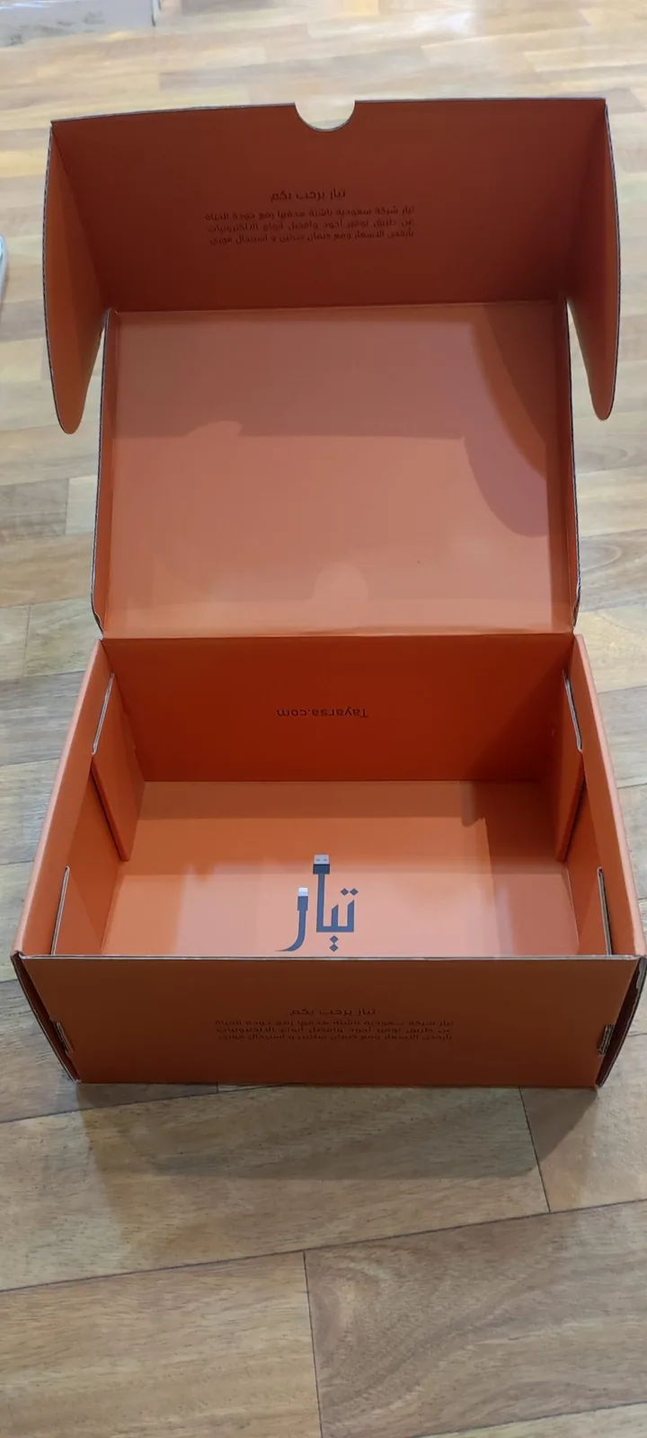 بوكس شحن كرتوني برتقالي مفتوح تظهر فيه الطباعة الداخلية ونص الترحيب على الغطاء والشعار في القاع