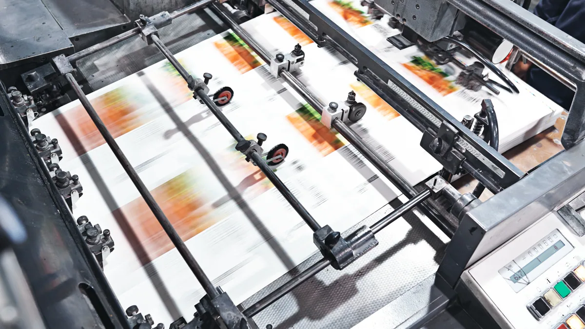 An offset printing press running sheets printed in four-colour process